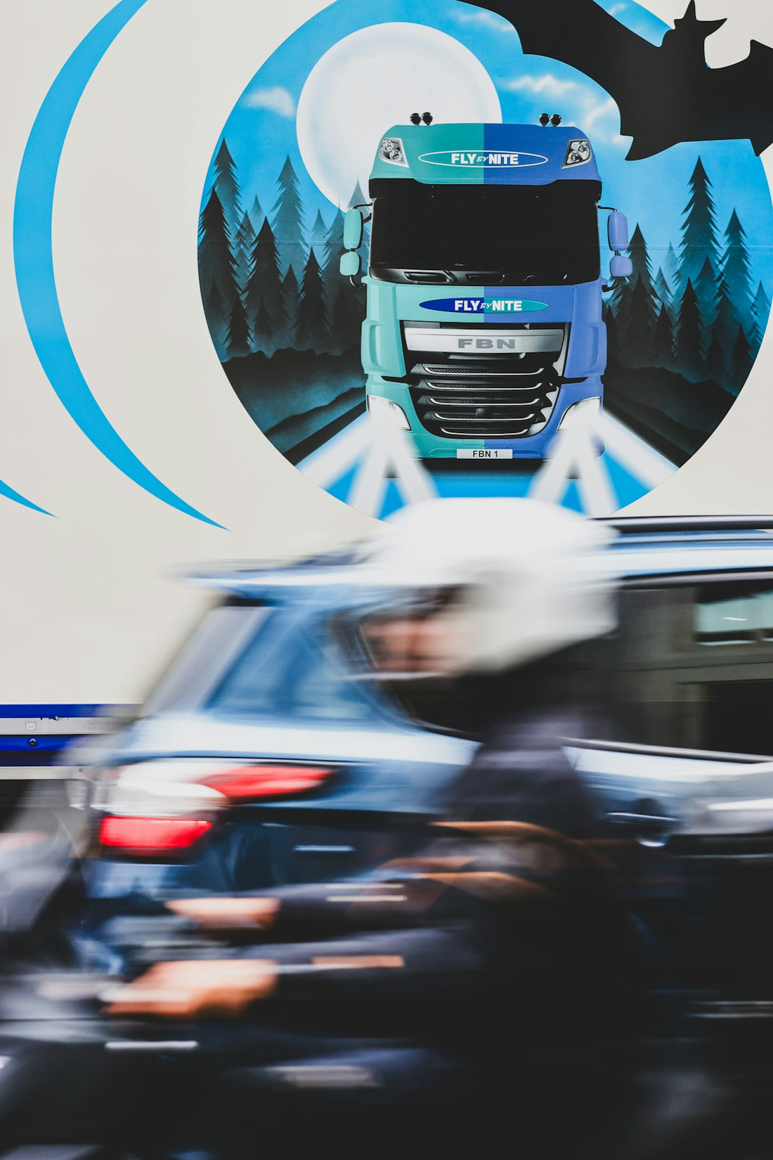 A large truck driving down a street next to a forest