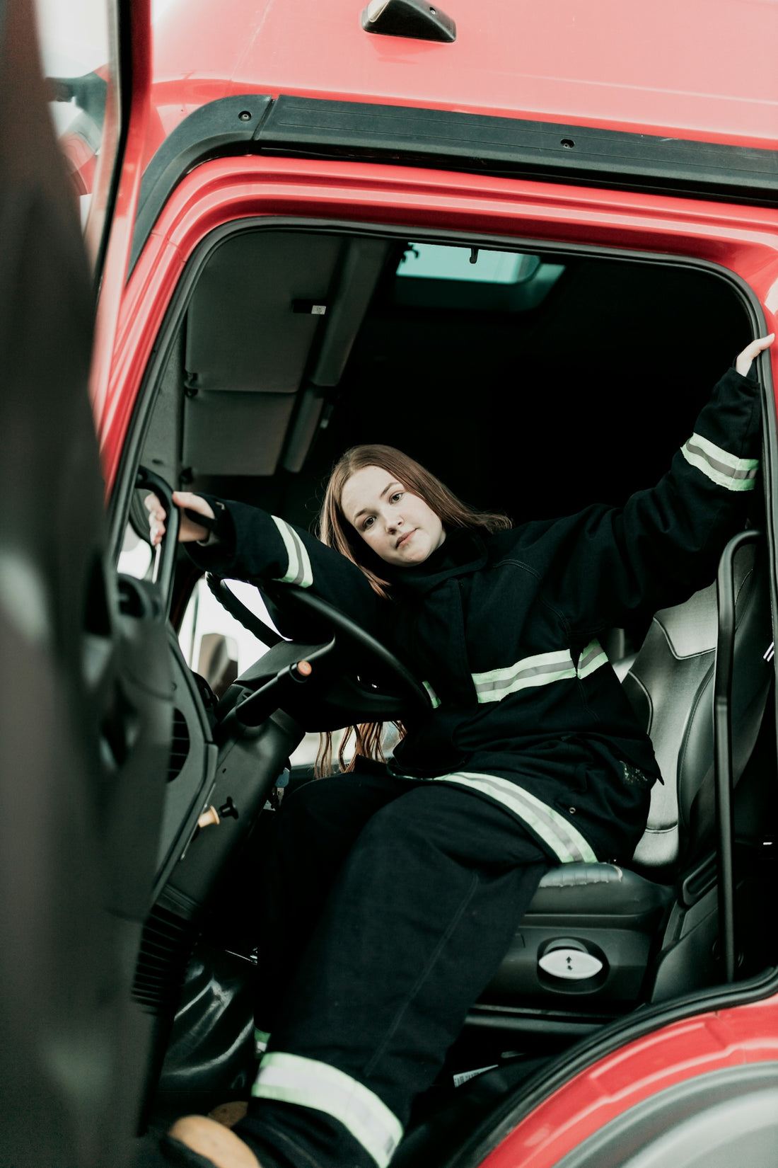 A woman sitting in the driver's seat of a red truck