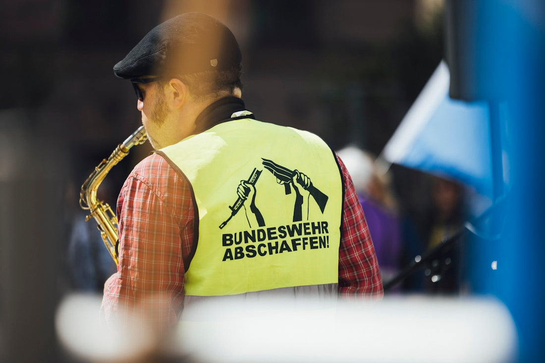 A musician plays saxophone, wearing a protest vest.